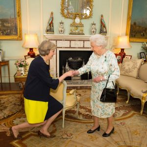 Theresa May kneels at Buckingham Palace in front of Queen Elizabeth II.