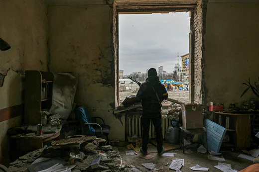A soldier from a local force in Kharkiv guards the building that was hit yesterday in a missile attack.